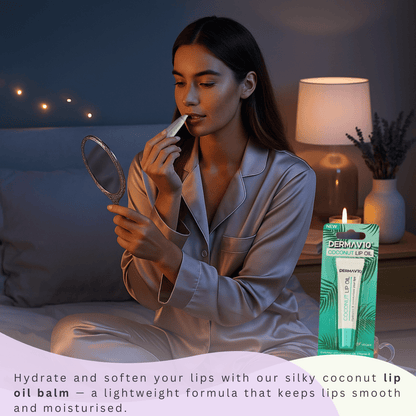 Woman applying coconut lip oil balm in a cosy bedroom setting with the Dermav10 Coconut Lip Oil product pack beside her; hydrating lightweight lip balm for smooth, moisturised lips