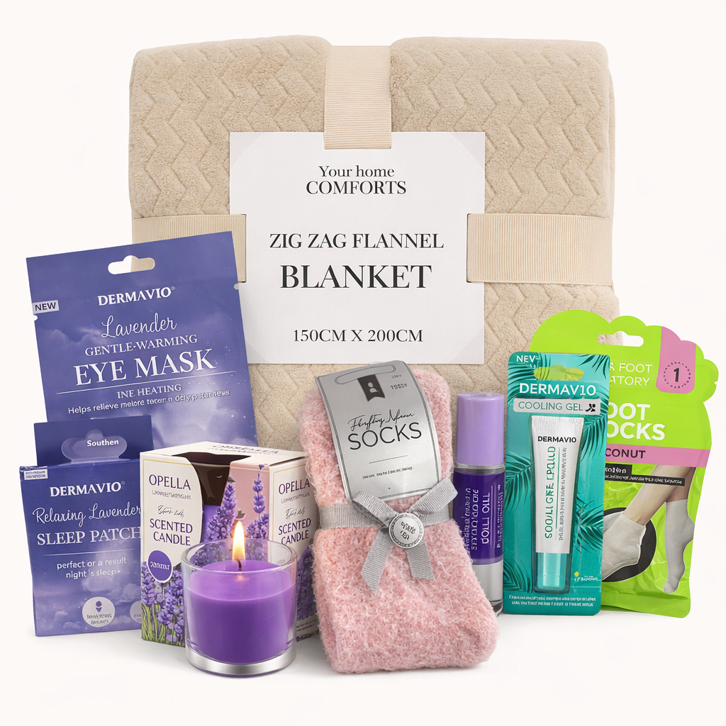 Cozy comfort gift set with soft flannel blanket, lavender eye mask, scented candle, fluffy socks, foot care products and sleep accessories on white background.